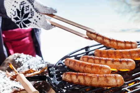 Grillwurst wird mit Grillzange gegrillt